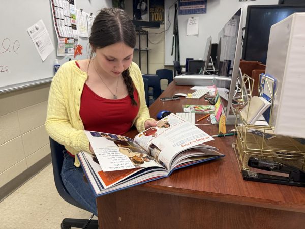 Junior Emily Browning looks through a recent yearbook for ideas. Browning, along with juniors Alexis Floyd and Myan Johnson, will lead the yearbook staff in 2026-27.